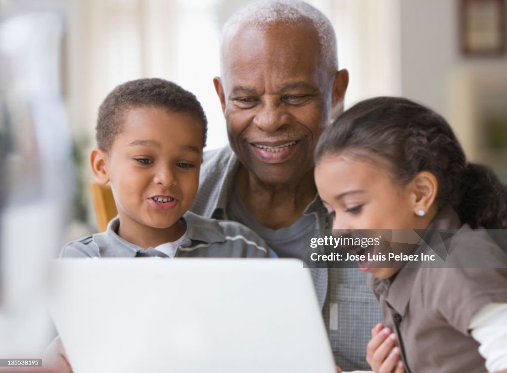 Grandfather and grandchildren using a laptop together