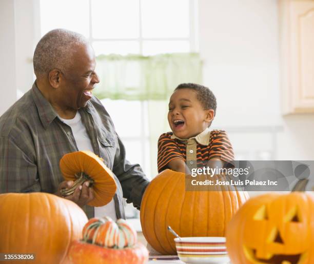 grandfather and grandson carving a pumpkin - grandparents raising grandchildren stock pictures, royalty-free photos & images