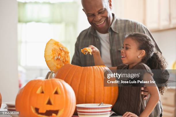 grandfather and granddaughter carving a pumpkin - pumpkin decoration stock pictures, royalty-free photos & images