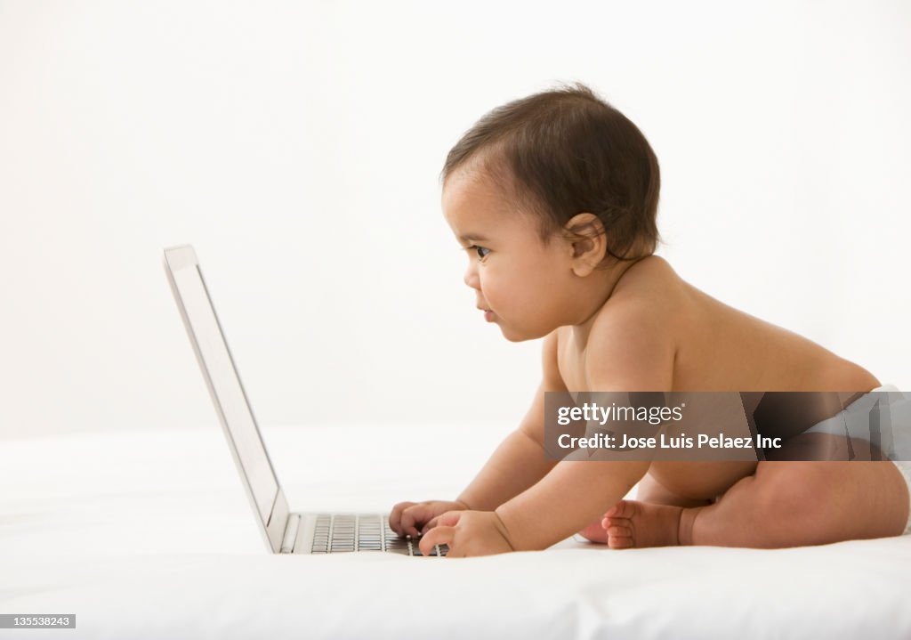 Mixed race baby girl looking at laptop