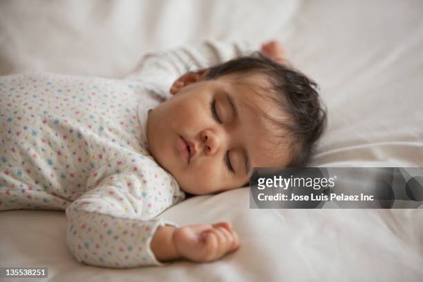 mixed race baby girl sleeping on bed - sleeping baby stockfoto's en -beelden