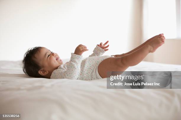 mixed race baby girl laying on bed - supino foto e immagini stock