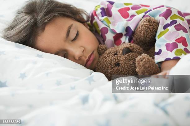 mixed race girl sleeping in bed with teddy bear - child teddy bear stock-fotos und bilder