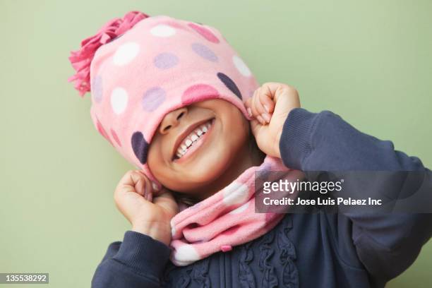 mixed race girl putting on knit cap - girl scarf bildbanksfoton och bilder