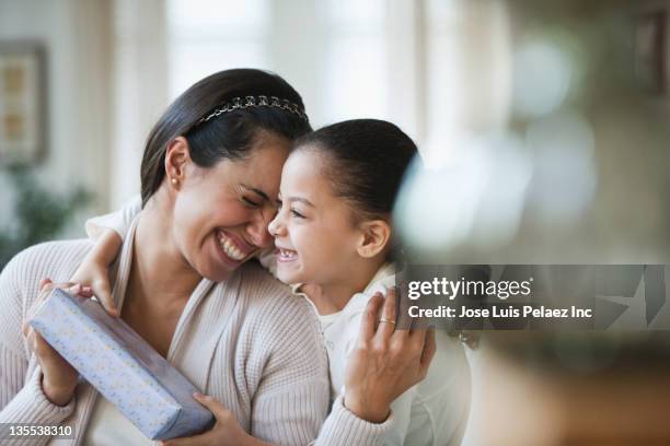 hispanic girl giving mother birthday gift - surprised mum stock pictures, royalty-free photos & images