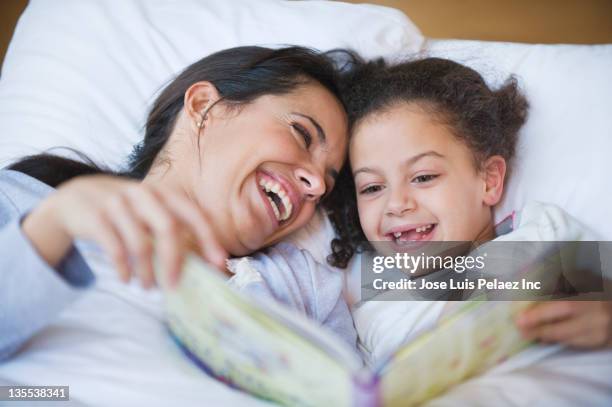 hispanic mother reading book to daughter - family with one child mother bonding family adult daughter focus on background leisure stock-fotos und bilder