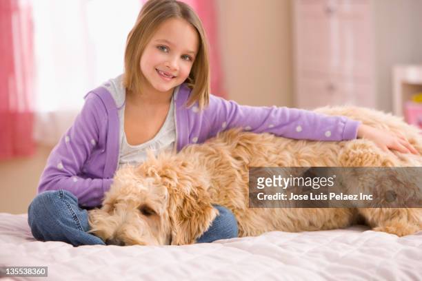 mixed race girl sitting on bed with dog - soltanto un animale foto e immagini stock