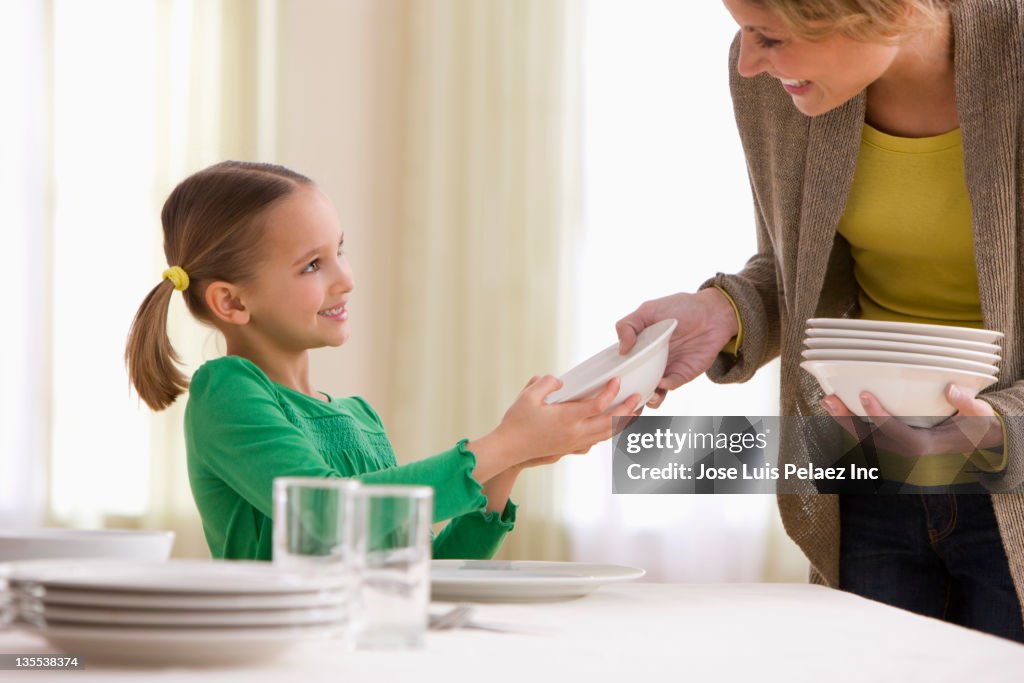 Mother and daughter setting the table