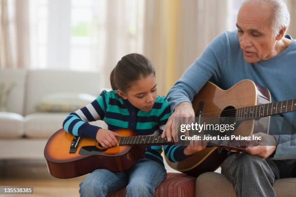 grandfather teaching granddaughter how to play guitar - teach muziekinstrument stockfoto's en -beelden