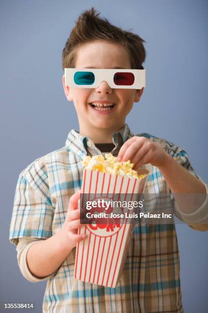 caucasian boy in 3-d glasses eating popcorn - kinosaal stock-fotos und bilder