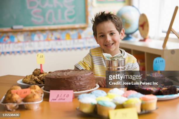 caucasian boy looking at baked goods for sale - bake sale stock pictures, royalty-free photos & images