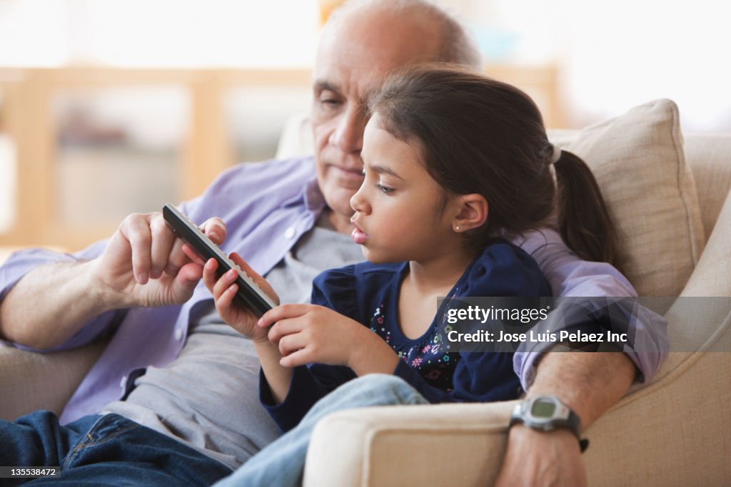 Grandfather and granddaughter watching television together