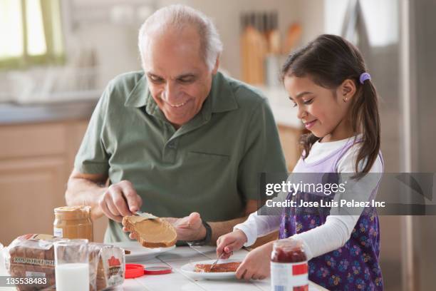 grandfather and granddaughter making sandwiches - marmelade machen stock-fotos und bilder