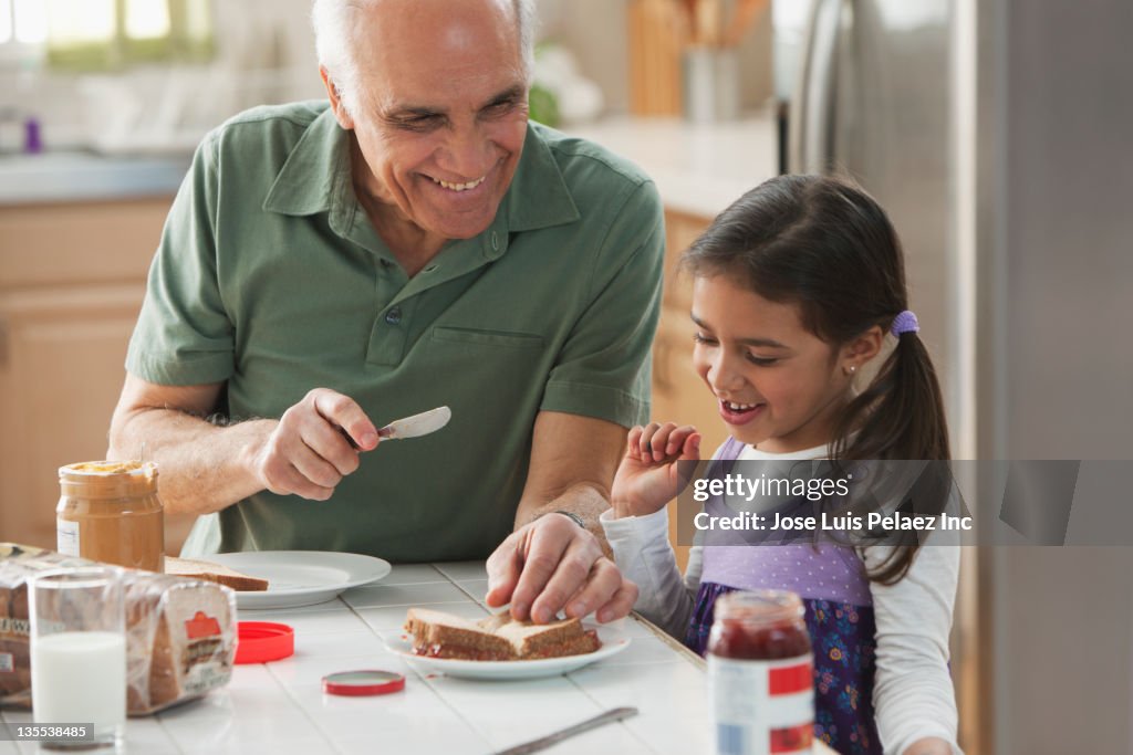 Grandfather and granddaughter making sandwiches