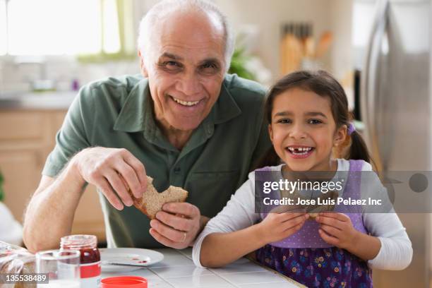 grandfather and granddaughter eating sandwiches - sandwich generation stock pictures, royalty-free photos & images