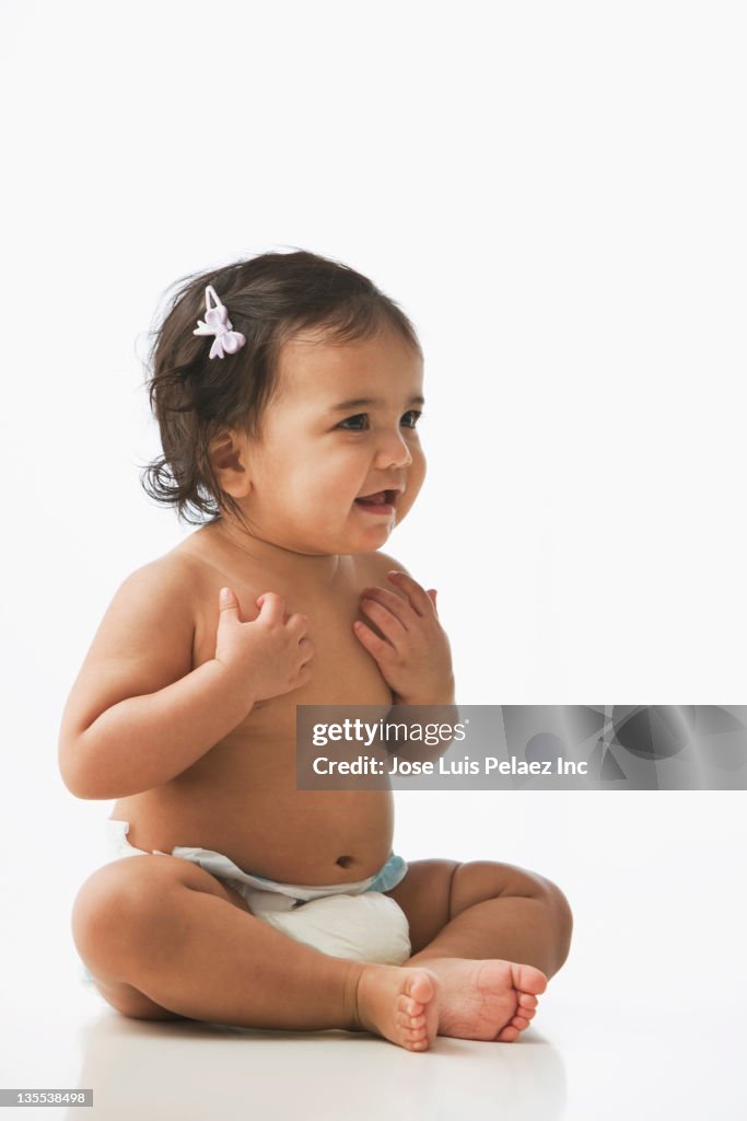 Hispanic baby girl sitting on floor