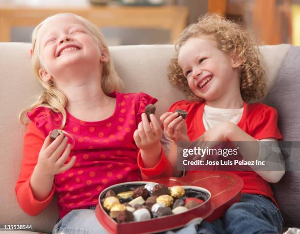 caucasian girls eating valentine's candy - chocolate heart stockfoto's en -beelden