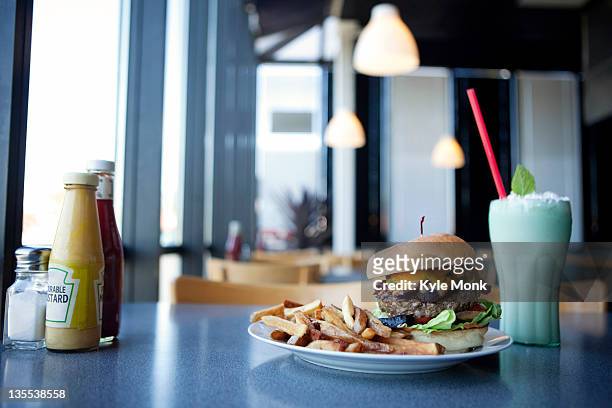 cheeseburger, french fries and milkshake in diner - burger and fries stockfoto's en -beelden