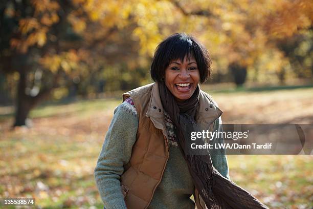 smiling black woman standing in autumn leaves - vest stock pictures, royalty-free photos & images