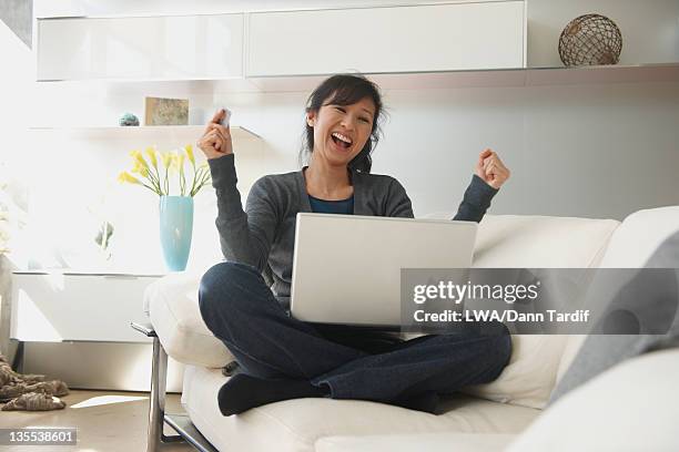 chinese woman sitting with laptop cheering - crédit consommation photos et images de collection