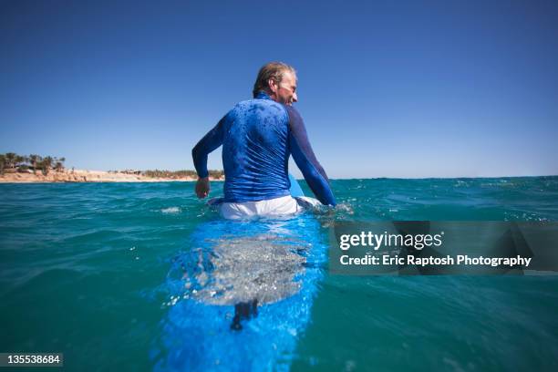 caucasian man floating on surfboard - sitting on surfboard ストックフォトと画像