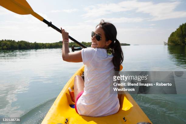 hispanic woman paddling kayak - summer kayaking stock pictures, royalty-free photos & images