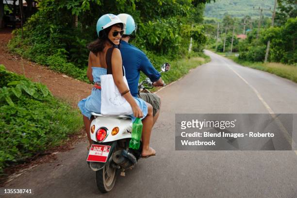 couple riding scooter in remote area - ko lanta stockfoto's en -beelden