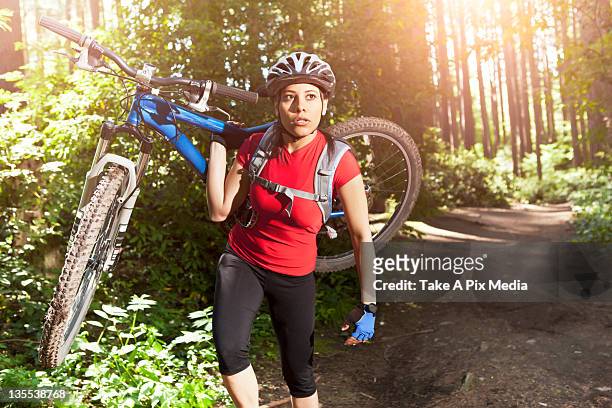 hispanic woman carrying mountain bike in forest - carrying bike stock pictures, royalty-free photos & images