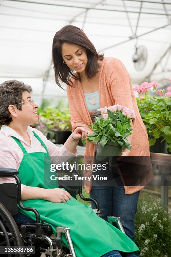 Caucasian worker in wheelchair helping customer in nursery Caucasian worker in wheelchair helping customer in nursery