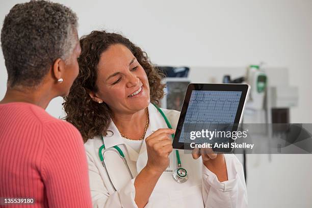 doctor showing patient test results on digital tablet - kardiologe stock-fotos und bilder