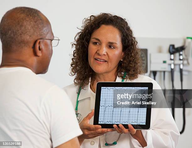 doctor showing patient test results on digital tablet - preventive care stock pictures, royalty-free photos & images