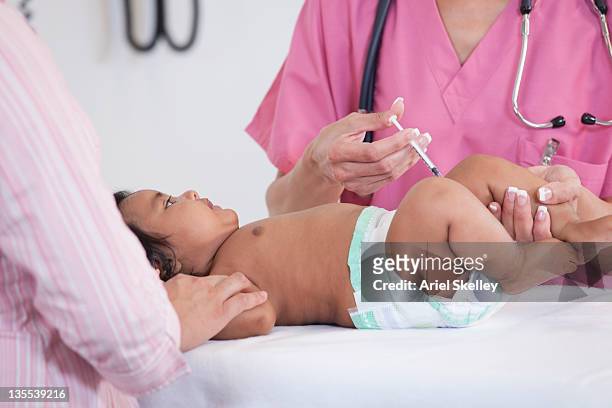 doctor giving baby injection in doctor's office - ariel shot stockfoto's en -beelden