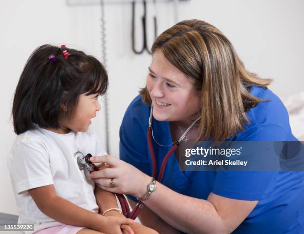 doctor listening to girl's breathing in doctor's office - infirmier praticien photos et images de collection