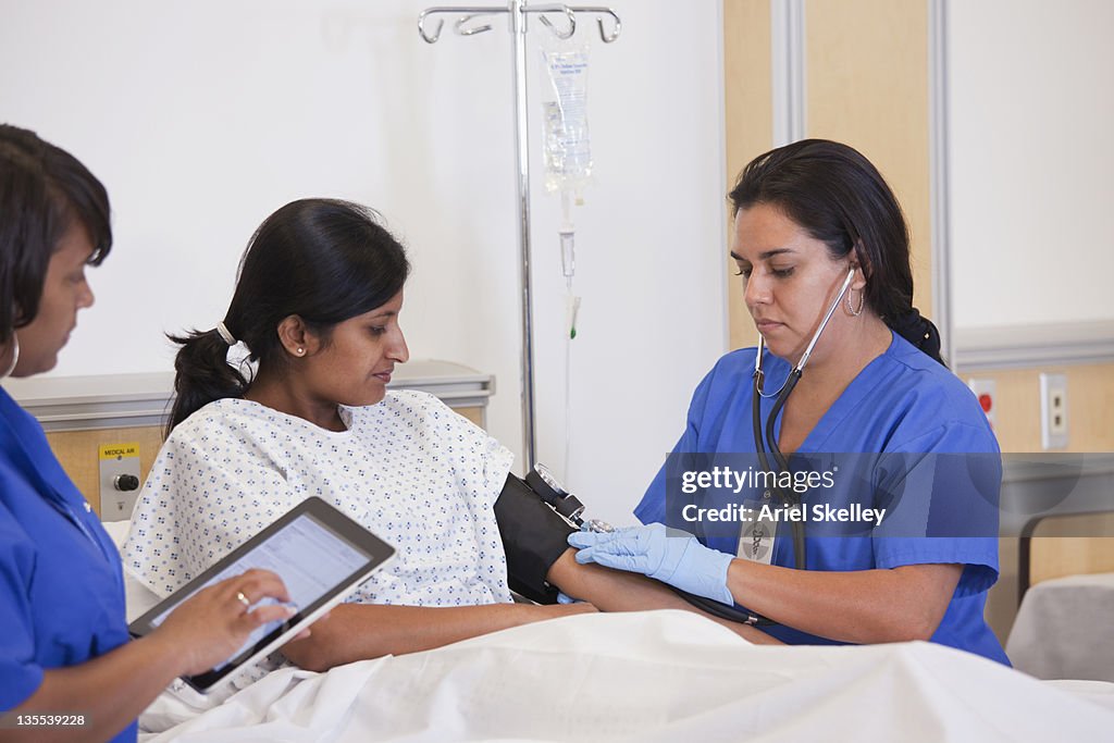 Nurse taking patient's blood pressure in hospital