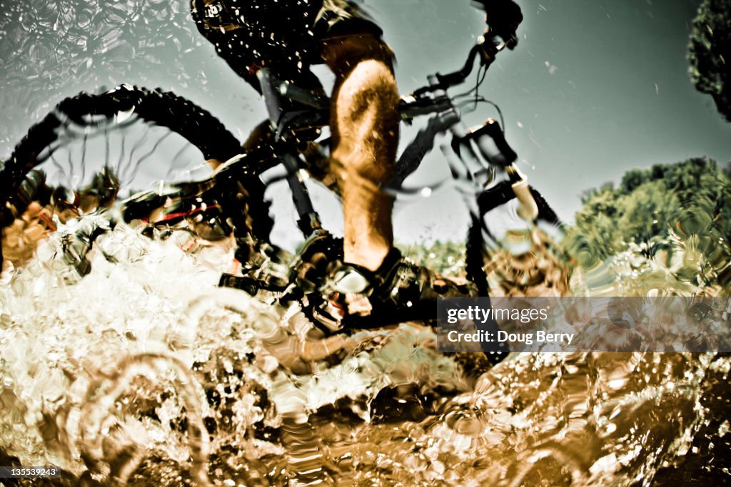 Man riding mountain bike through water