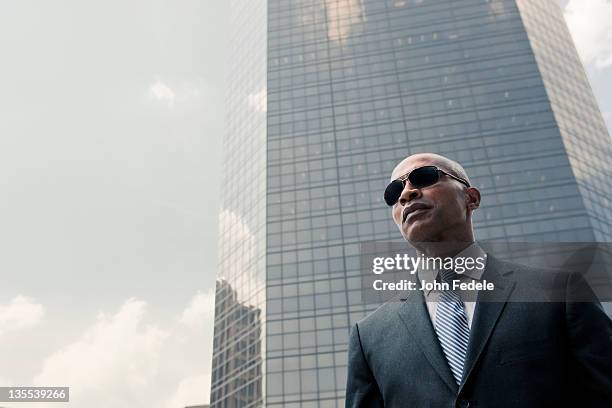 black businessman standing near highrise - black suit sunglasses stock pictures, royalty-free photos & images