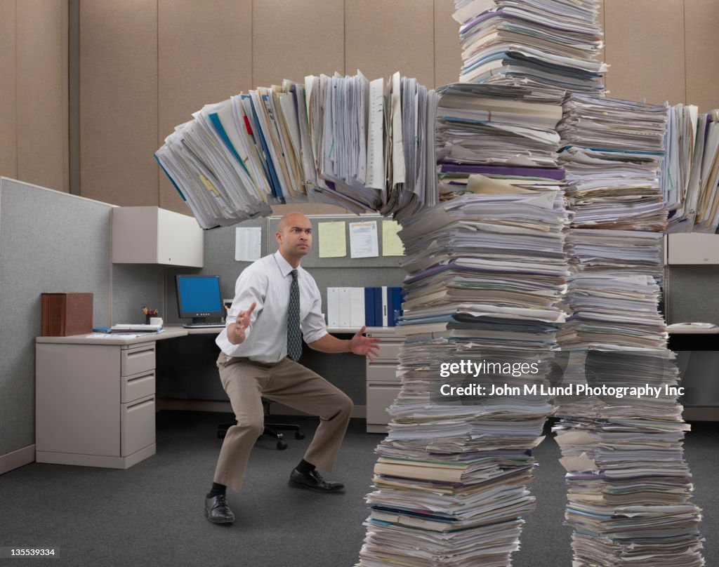 Mixed race businessman facing paperwork monster