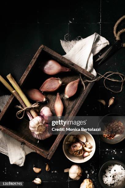 fresh garlic heads in wooden box with shallots chillies and salt flakes on black tiles - allium stock pictures, royalty-free photos & images