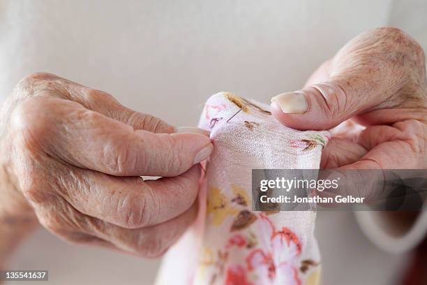 detail of a senior woman stitching fabric - mani fili foto e immagini stock