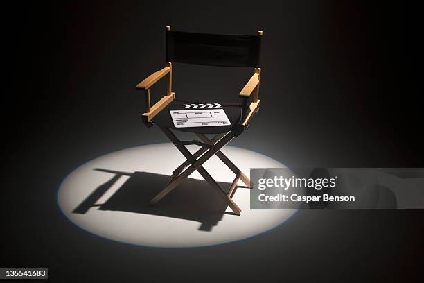 a spot lit directors chair and a clapper board - regisseurstoel stockfoto's en -beelden