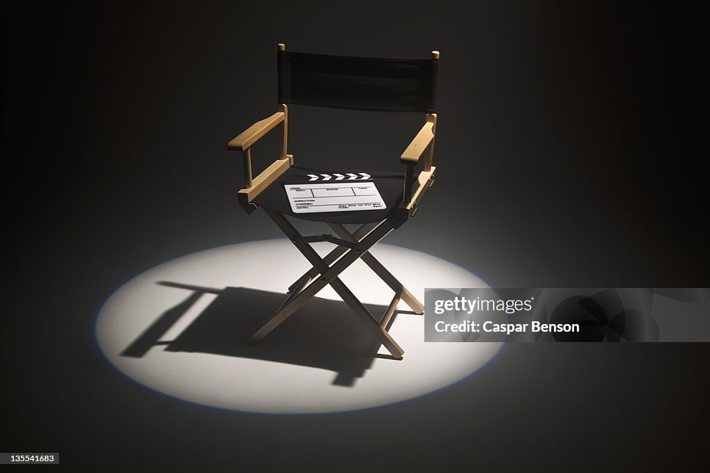 A spot lit directors chair and a clapper board