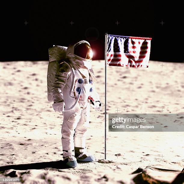 an astronaut next to an american flag on the moon - astronaut moon stockfoto's en -beelden