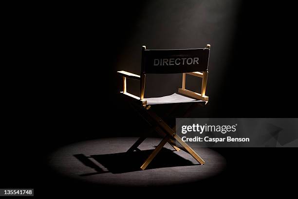 a spot lit directors chair - director's chair stock-fotos und bilder