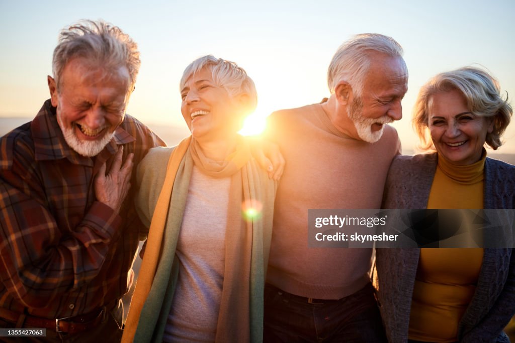 Happy mature couples talking while walking in autumn day.