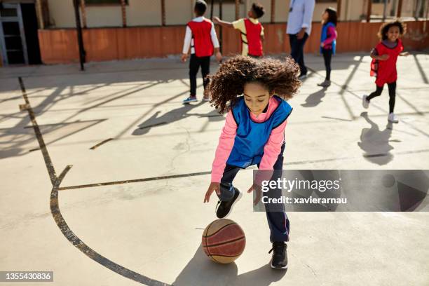 active multiracial schoolgirl playing basketball outdoors - school life balance stock pictures, royalty-free photos & images