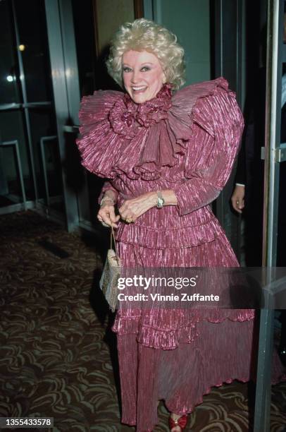 American comedian and actress Phyllis Diller , wearing a burgundy dress with high shoulders and ruffles, attends the 32nd Annual Thalians Ball, held...