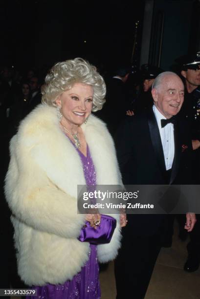 American comedian and actress Phyllis Diller , wearing a purple outfit beneath a white fur coat, and American lawyer Robert P Hastings attend the...