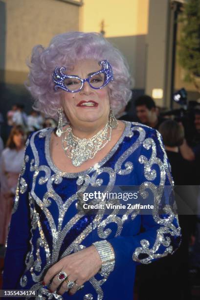 Australian actor and comedian Barry Humphries, in character as Dame Edna Everage, wearing a blue evening dress with silver embroidery, attends the...