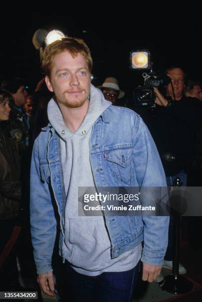 American actor Eric Stoltz, wearing a Levi's denim jacket over a grey hooded top, attends an event, circa 1990.