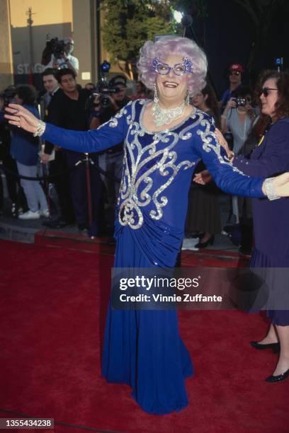 Australian actor and comedian Barry Humphries, in character as Dame Edna Everage, wearing a blue evening dress with silver embroidery, attends the...
